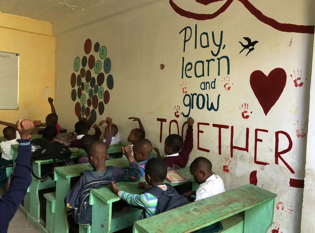 Klassenraum mit dem Wandbild „Play, learn and grow together“