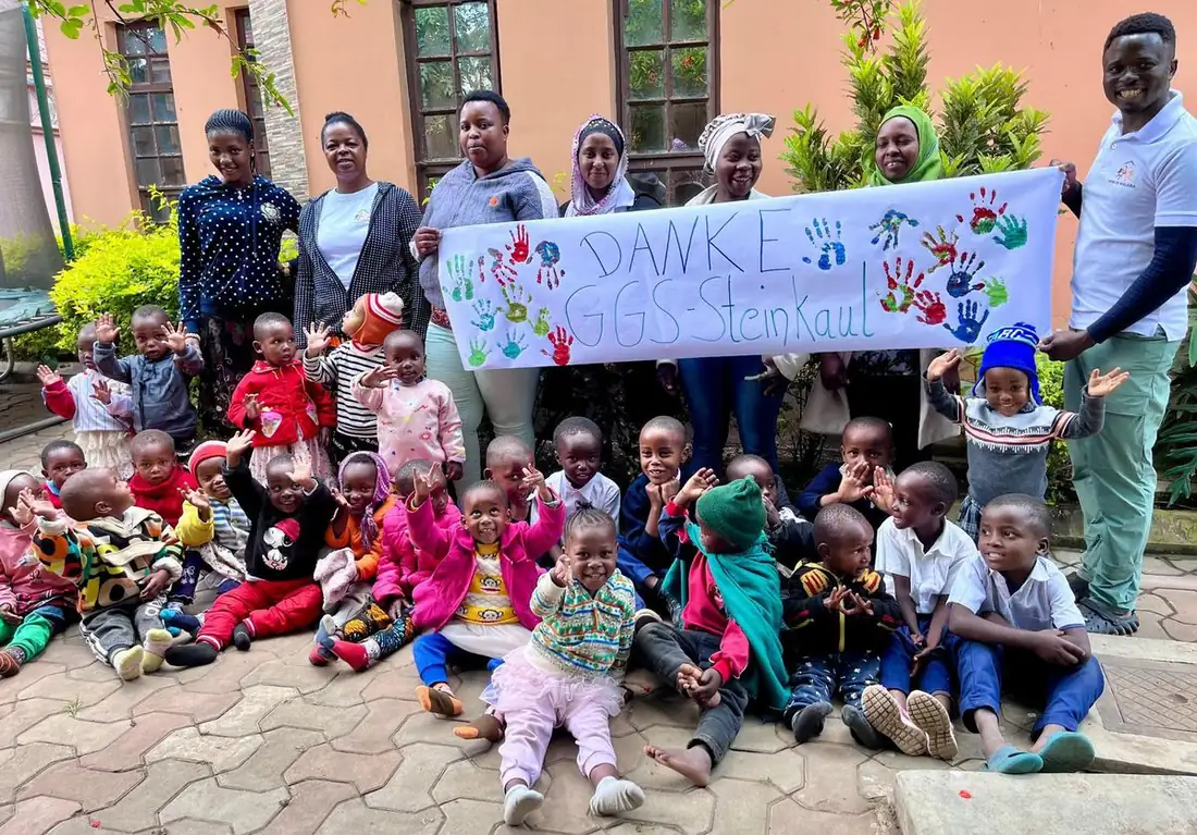Kinder mit selbst gemaltem Banner im Projekthaus